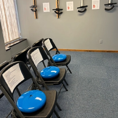 Physical rehabilitation room, where chairs and various items such as elastic bands and cushions specifically designed for rehabilitating parts of the body are observed.